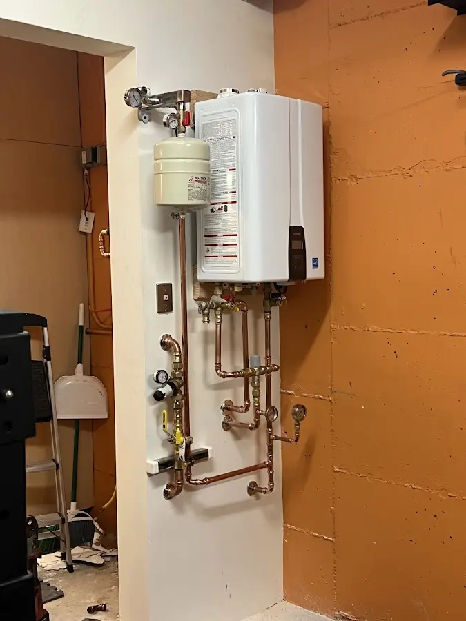 Plumbing technician inspecting water heater connections in Stowe